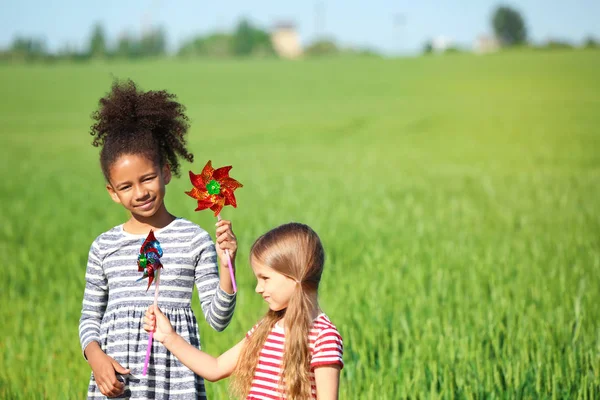 Boldog kis lányok játék szélmalmok a zöld mezőben — Stock Fotó