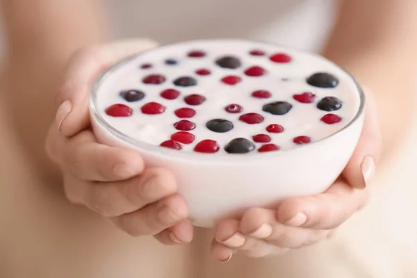 Mujer joven sosteniendo tazón de vidrio con yogur, primer plano — Foto de Stock