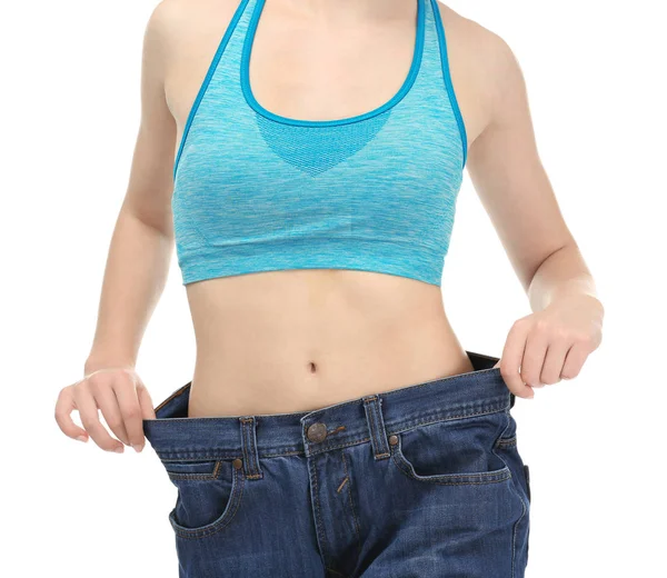 Genç kadın beyaz arka plan üzerinde büyük boy kot pantolon. Diyet kavramı