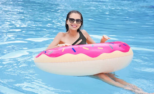 Hermosa joven con rosquilla inflable en la piscina — Foto de Stock