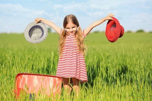 Little girl with suitcase in green field — Stock Photo, Image