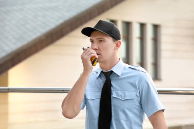Male security guard with portable radio, outdoors clipart