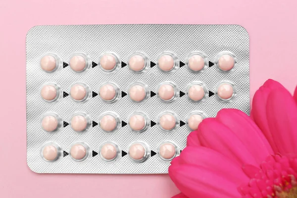 Blister de pílulas contraceptivas com flor no fundo de cor — Fotografia de Stock