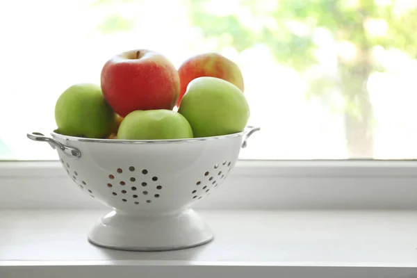 Colander with fresh apples on windowsill — Stock Photo, Image