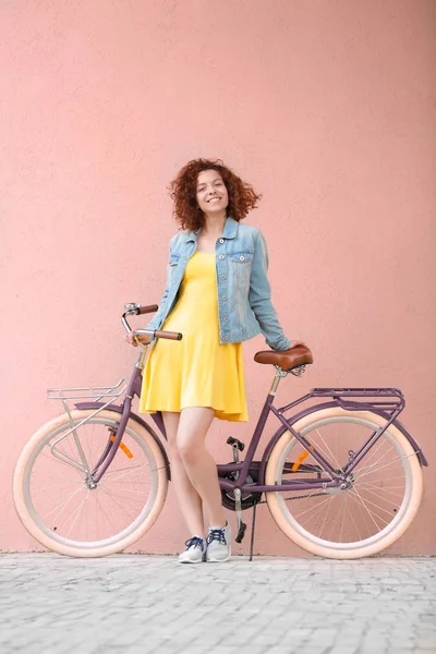 Schöne junge Frau mit Fahrrad auf Farbwand Hintergrund — Stockfoto