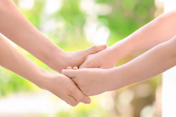 Mother and daughter holding hands together on blurred background, closeup — Stock Photo, Image