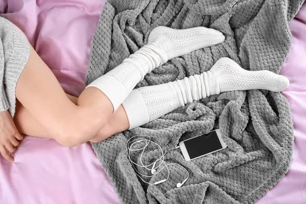 Jovem mulher de meias deitada na cama com telefone, vista superior — Fotografia de Stock