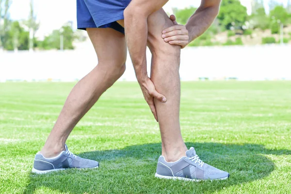 Junger Mann leidet unter Schmerzen im Bein, im Freien — Stockfoto