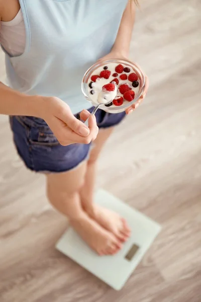 Giovane donna sul pavimento squame mangiare yogurt a casa — Foto Stock