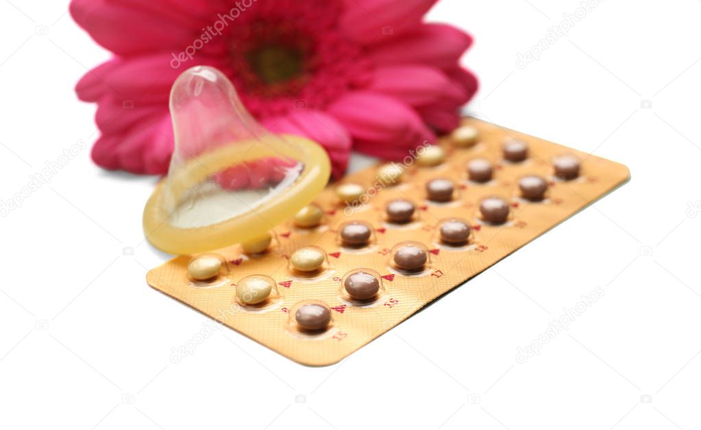 Contraception concept. Pills, condom and flower on white background