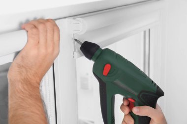 Genç adam pencere perde kapalı yükleme