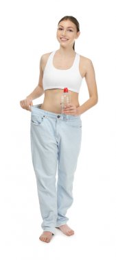 Beyaz arka plan üzerinde su şişe büyük boy kot pantolon güzel ve genç birbayan. Diyet kavramı