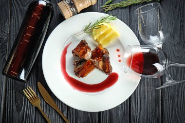 Lezzetli kaburga, bir şişe şarap ve bardak tablo ile plaka