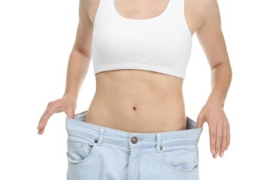 Genç kadın beyaz arka plan üzerinde büyük boy kot pantolon. Diyet kavramı