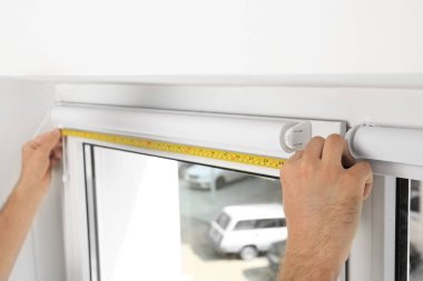 Genç adam pencere perde kapalı yükleme