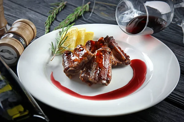 Assiette avec de délicieuses côtes, bouteille de vin et verres sur la table — Photo