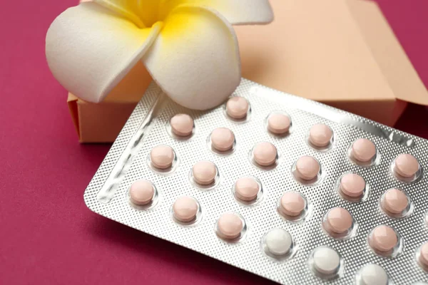 Pillole contraccettive con fiore su sfondo di colore — Foto Stock