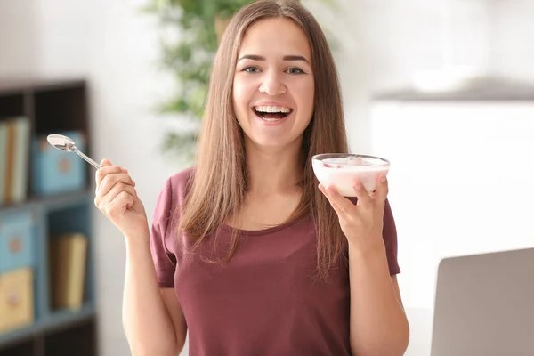 Mujer joven comiendo yogur sobre fondo borroso — Foto de Stock