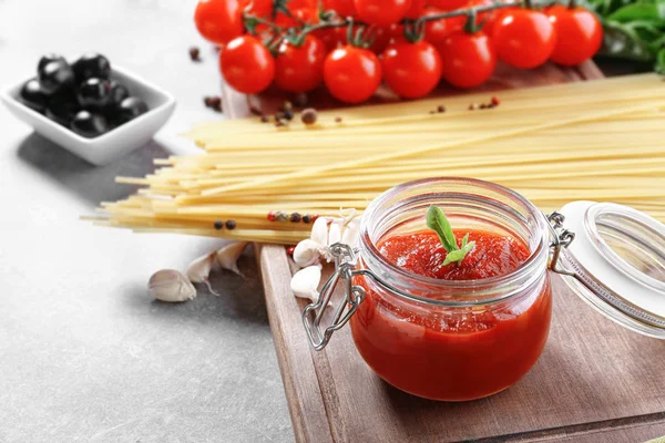 Glass jar with tasty tomato sauce and pasta