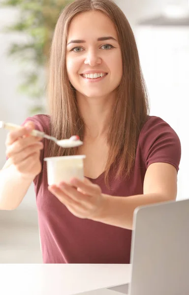 Ung kvinna äta yoghurt vid bord — Stockfoto