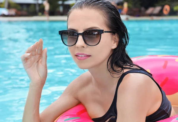 Hermosa joven con rosquilla inflable en la piscina —  Fotos de Stock