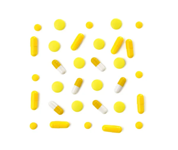 Různé žluté pilulky na bílém pozadí — Stock fotografie