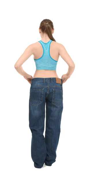 Jeune femme en jean oversize sur fond blanc. Concept de régime alimentaire — Photo