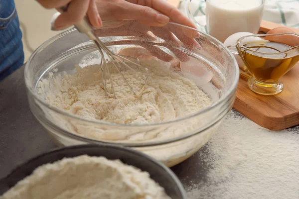 Женщина-шеф-повар делает тесто в стеклянной миске на кухонном столе — стоковое фото