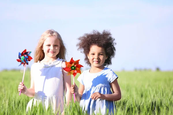 Szczęśliwy dziewczynki z wiatrakami zabawka zielony pole — Zdjęcie stockowe