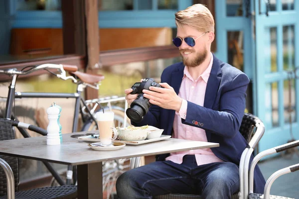 Young blogger working with camera at table, outdoors