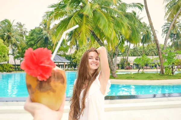 Cóctel de coco borroso y mujer joven en el fondo en el resort — Foto de Stock