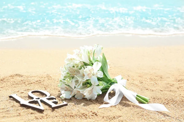 Schöner Strauß und Wortliebe auf Sand. Strandhochzeit-Konzept — Stockfoto