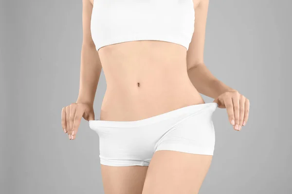 Young woman in underwear on gray background. Diet concept — Stock Photo, Image