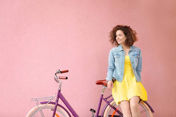 Vacker ung kvinna med cykel på färgbakgrund — Stockfoto