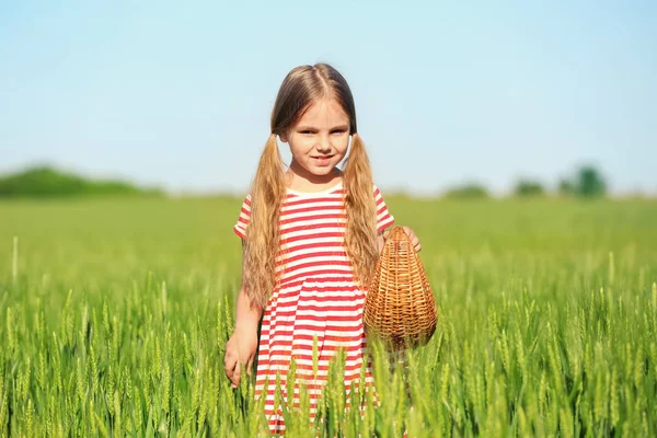 Счастливая маленькая девочка с корзинкой в зеленом поле — стоковое фото