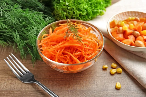 Schüssel mit leckerem Karottensalat auf Holztisch — Stockfoto