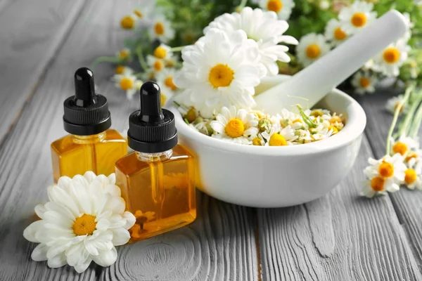 Essential oil and chamomile flowers — Stock Photo, Image