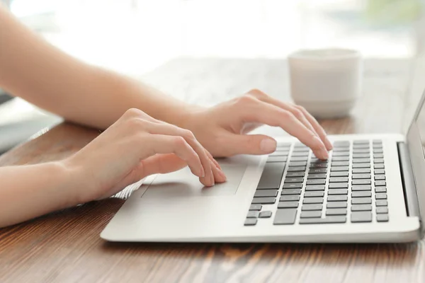 Mujer joven usando el ordenador portátil para buscar información en Internet en la mesa —  Fotos de Stock