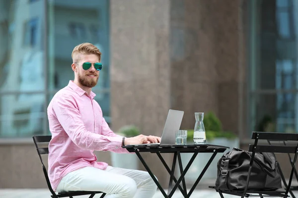Jeune blogueur avec ordinateur portable travaillant à table, à l'extérieur — Photo