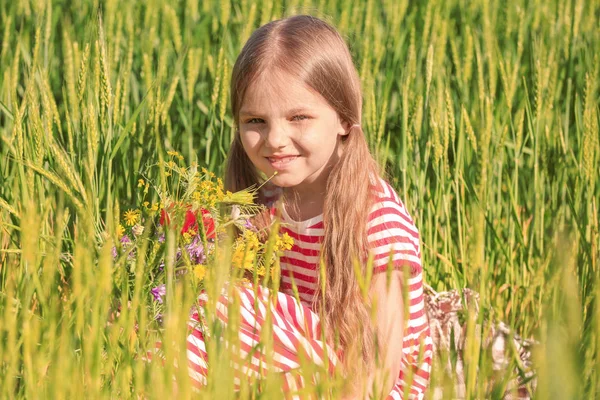 Little girl with bouquet of wildflowers in green field — Stock Photo, Image