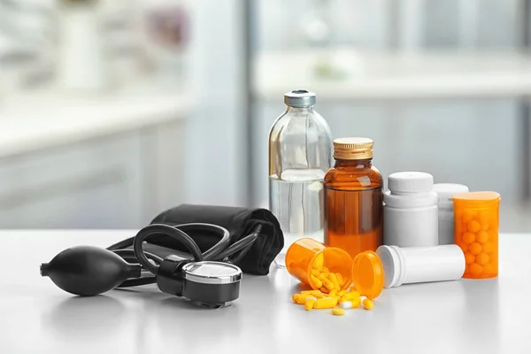 Plastic containers with pills, bottles and pressure meter on table — Stock Photo, Image