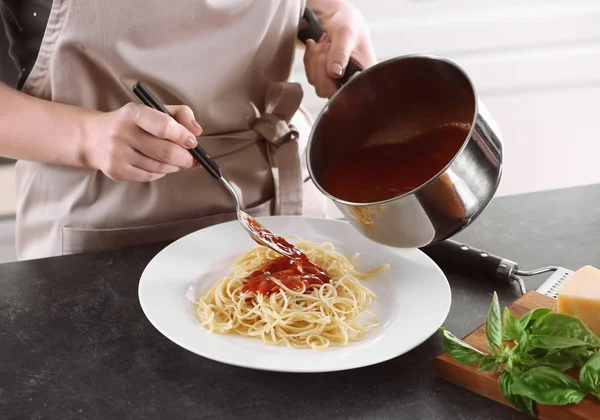 Женщина добавляет вкусный соус к макаронам — стоковое фото