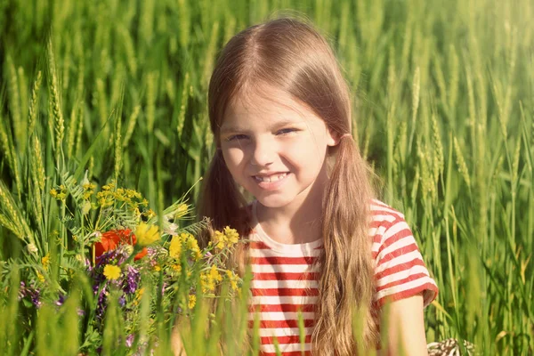 Meisje met boeket van wilde bloemen in groene veld — Stockfoto