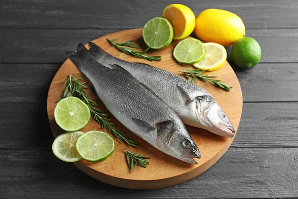 Pesce fresco con fette di agrumi su fondo di legno — Foto Stock