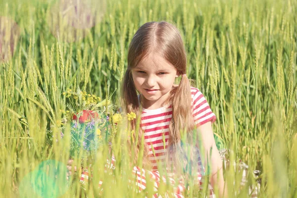 Gadis kecil dengan karangan bunga liar di lapangan hijau — Stok Foto