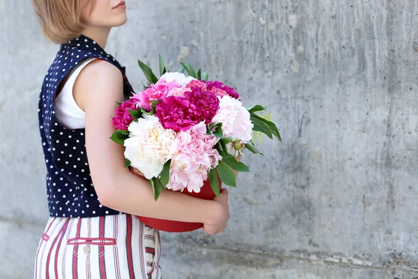 Young girl holding gift box with beautiful peonies on grunge background — Stock Photo, Image