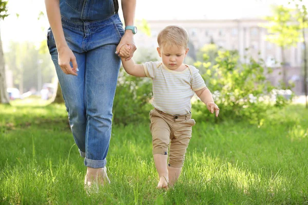 Madre y lindo bebé niño caminando sobre hierba verde en el parque — Foto de Stock