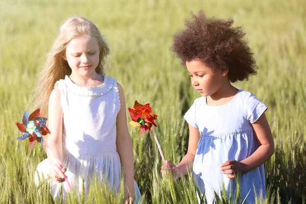 Glückliche kleine Mädchen mit Spielzeugwindmühlen auf der grünen Wiese — Stockfoto