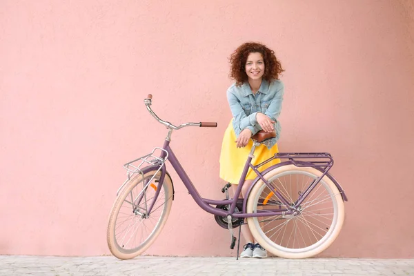 Vacker ung kvinna med cykel på färg vägg bakgrund — Stockfoto