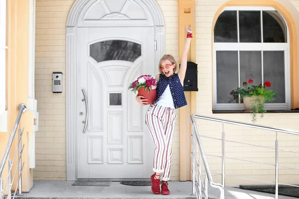 Mooi jong meisje permanent in de buurt van deur met pioenroos bloemen in doos van de gift, buitenshuis — Stockfoto